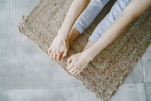 Free A person stretching on a woven mat. Close-up view of hands and feet in relaxed yoga pose. Stock Photo