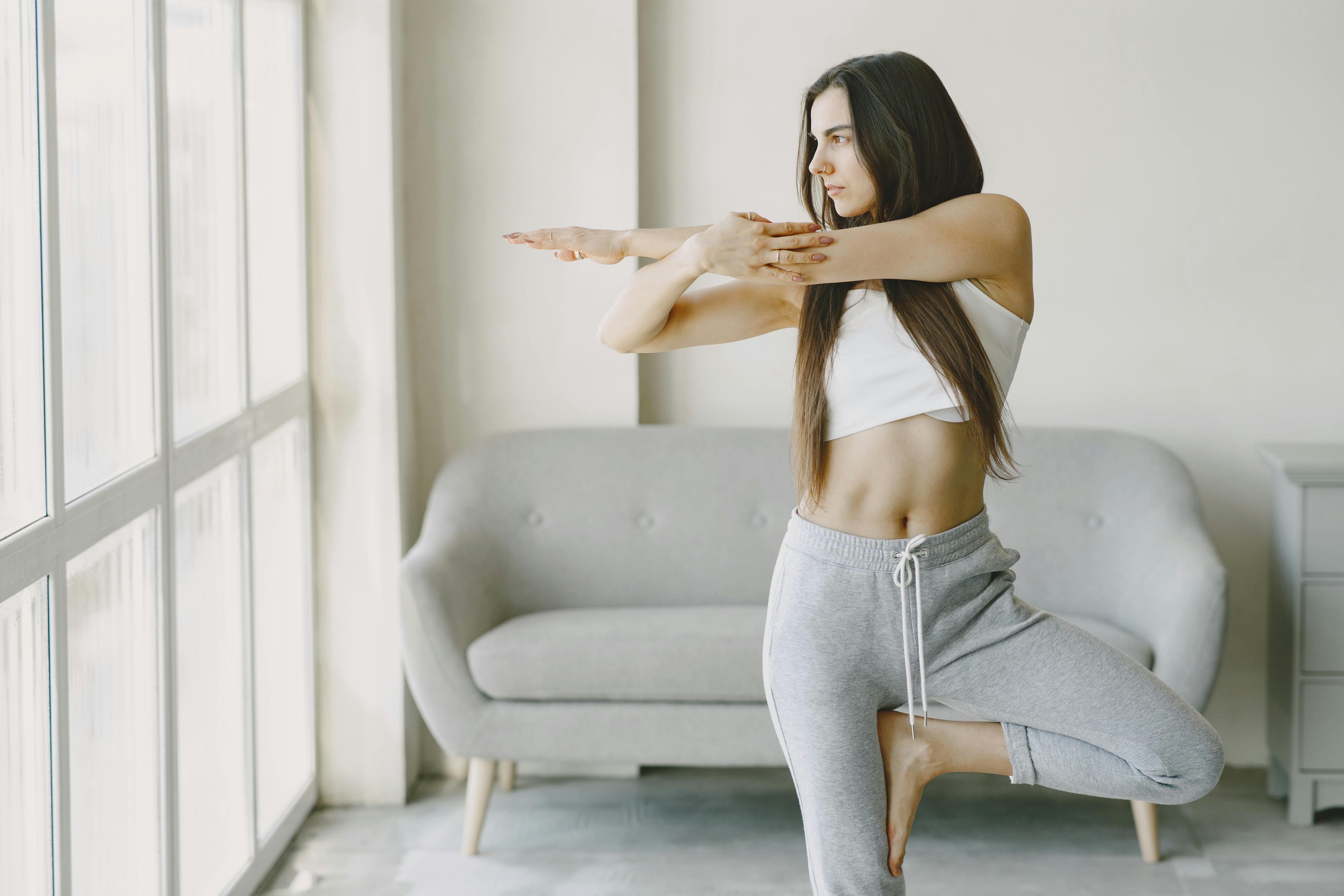 A woman performs a yoga pose at home, focusing on balance and tranquility.