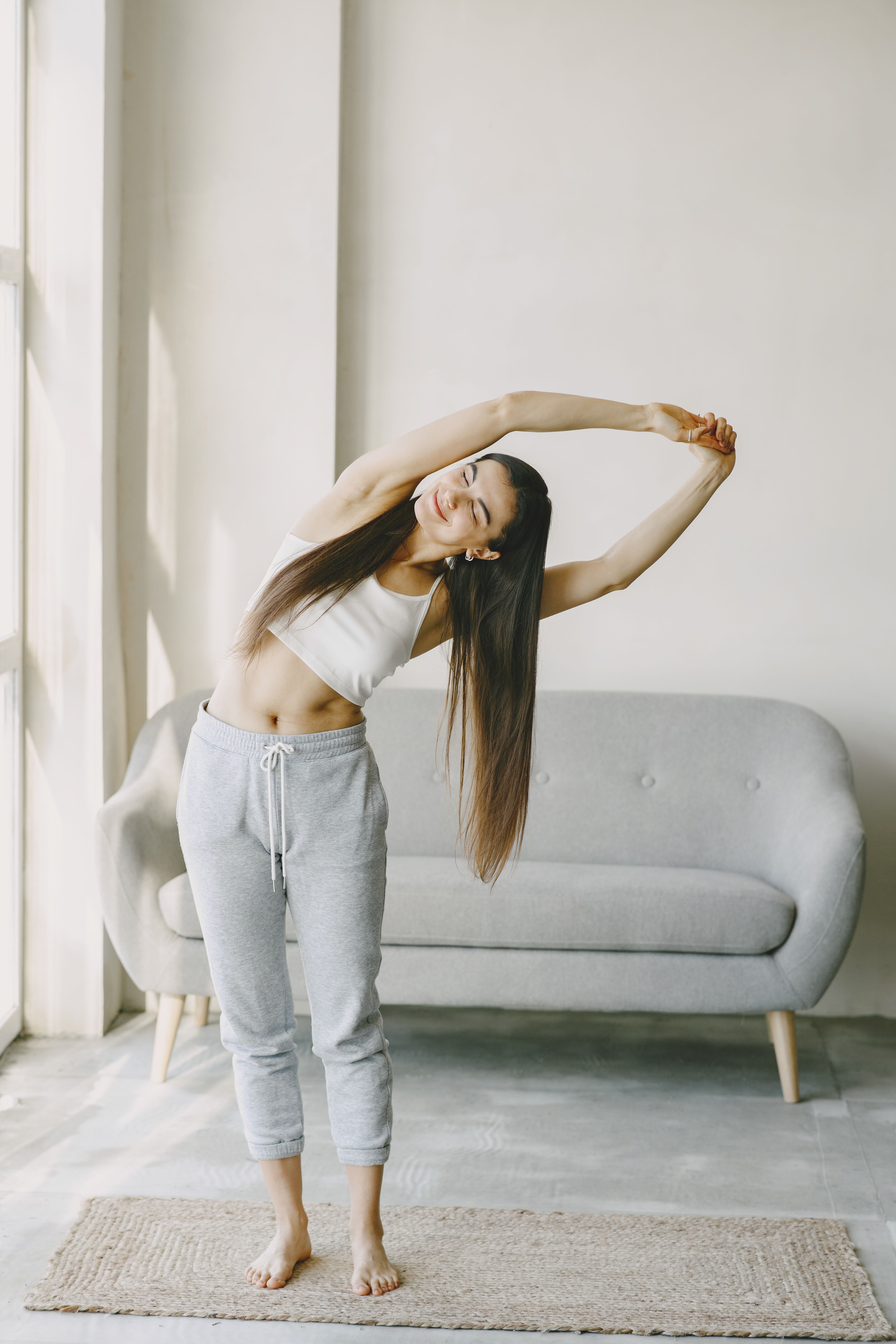 Woman in a standing side bend at home, photo by Gustavo Fring on Pexels