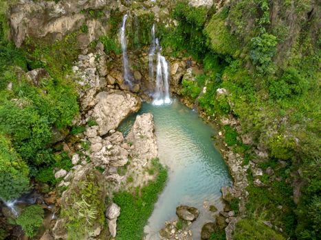 Discover the tranquil beauty of a secluded waterfall surrounded by lush greenery and rocky formations.