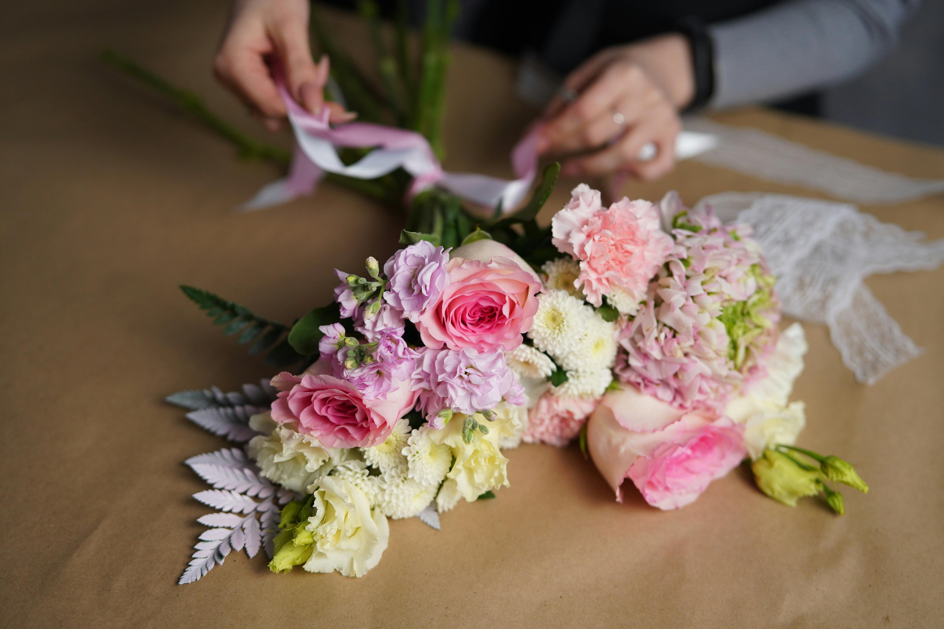 florist tying ribbon on bouquet of flowers