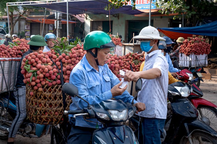 A Man On A Motorcycle Transporting Fruits