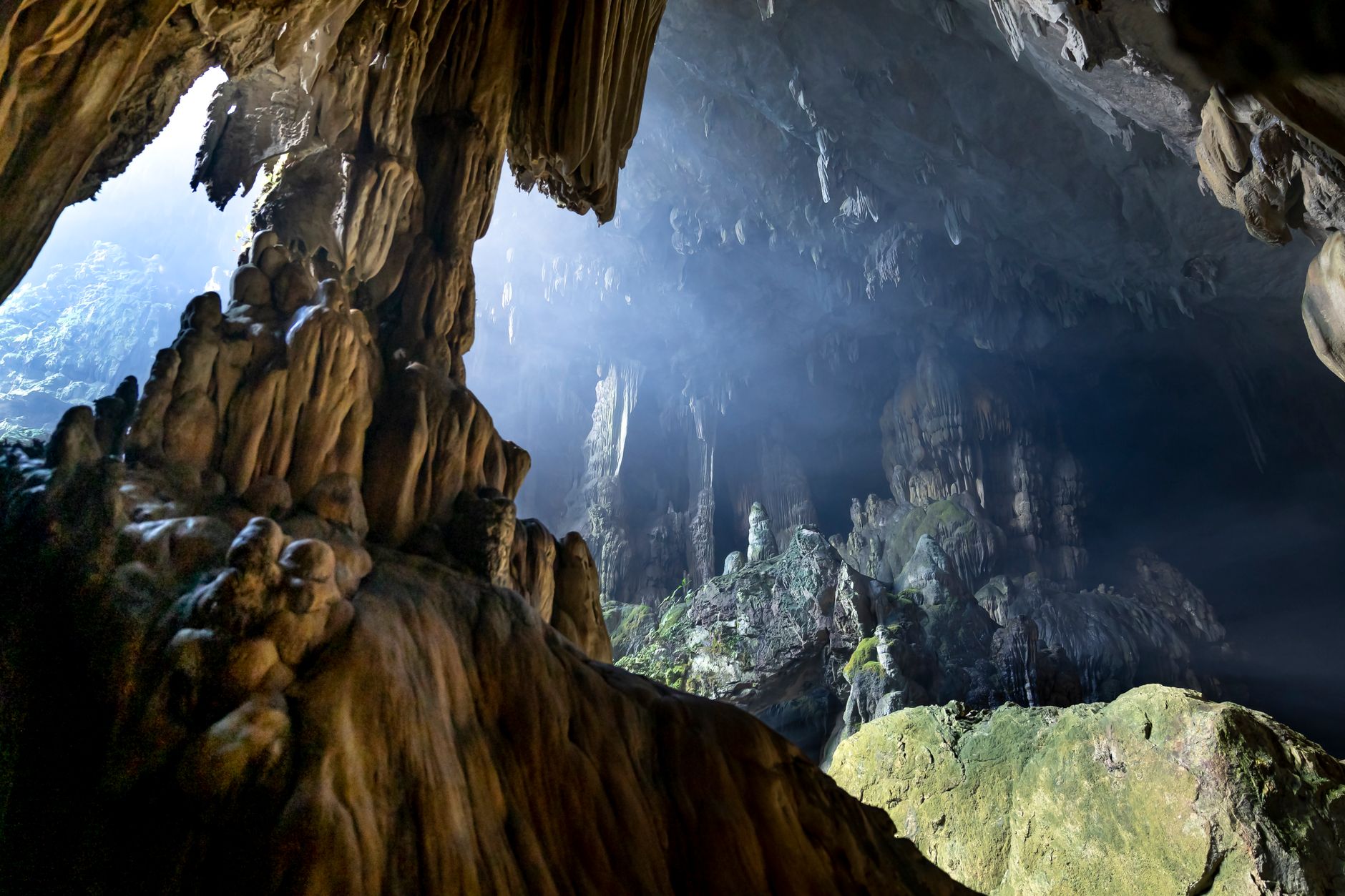 Explore the breathtaking formations of a limestone cave featuring dramatic stalagmites and sunlight peeking through.