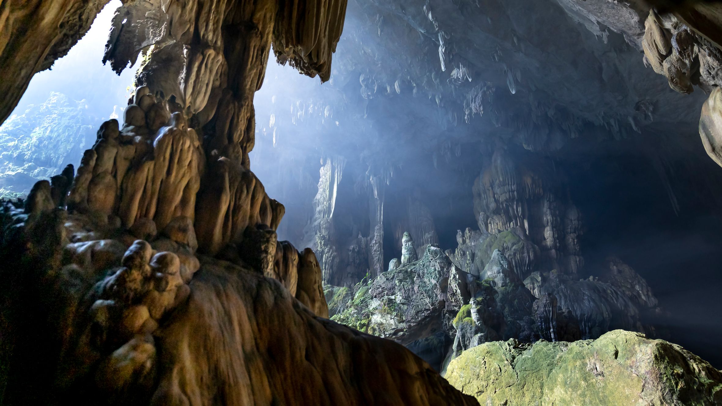 Explore the breathtaking formations of a limestone cave featuring dramatic stalagmites and sunlight peeking through.