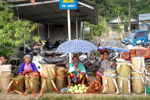 Women selling woven baskets at a local market under colorful umbrellas.