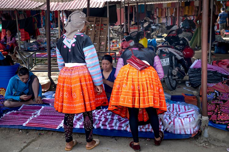 Two Women Buying Fabric At The Market 