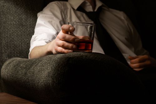 Free A person relaxing on a sofa, holding a glass of whiskey, creating a moody and intimate atmosphere. Stock Photo