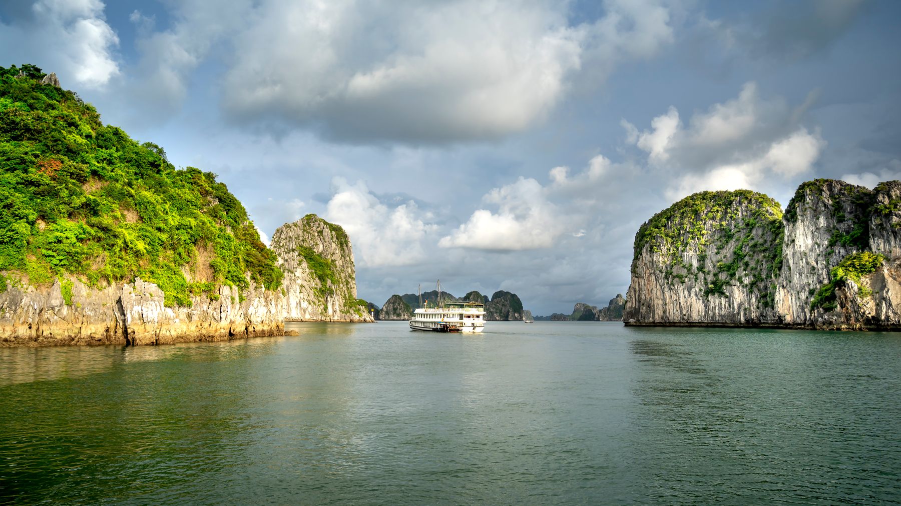 Khám phá những khối đá tuyệt đẹp và làn nước tĩnh lặng của Ha Long Bay, với hình ảnh du thuyền dưới bầu trời đầy ấn tượng.