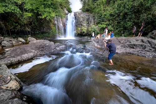 People near Waterfall in Rock Landscape