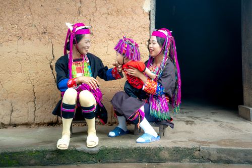 Free Two women and a child in colorful traditional clothing, sitting outdoors, smiling and bonding. Stock Photo