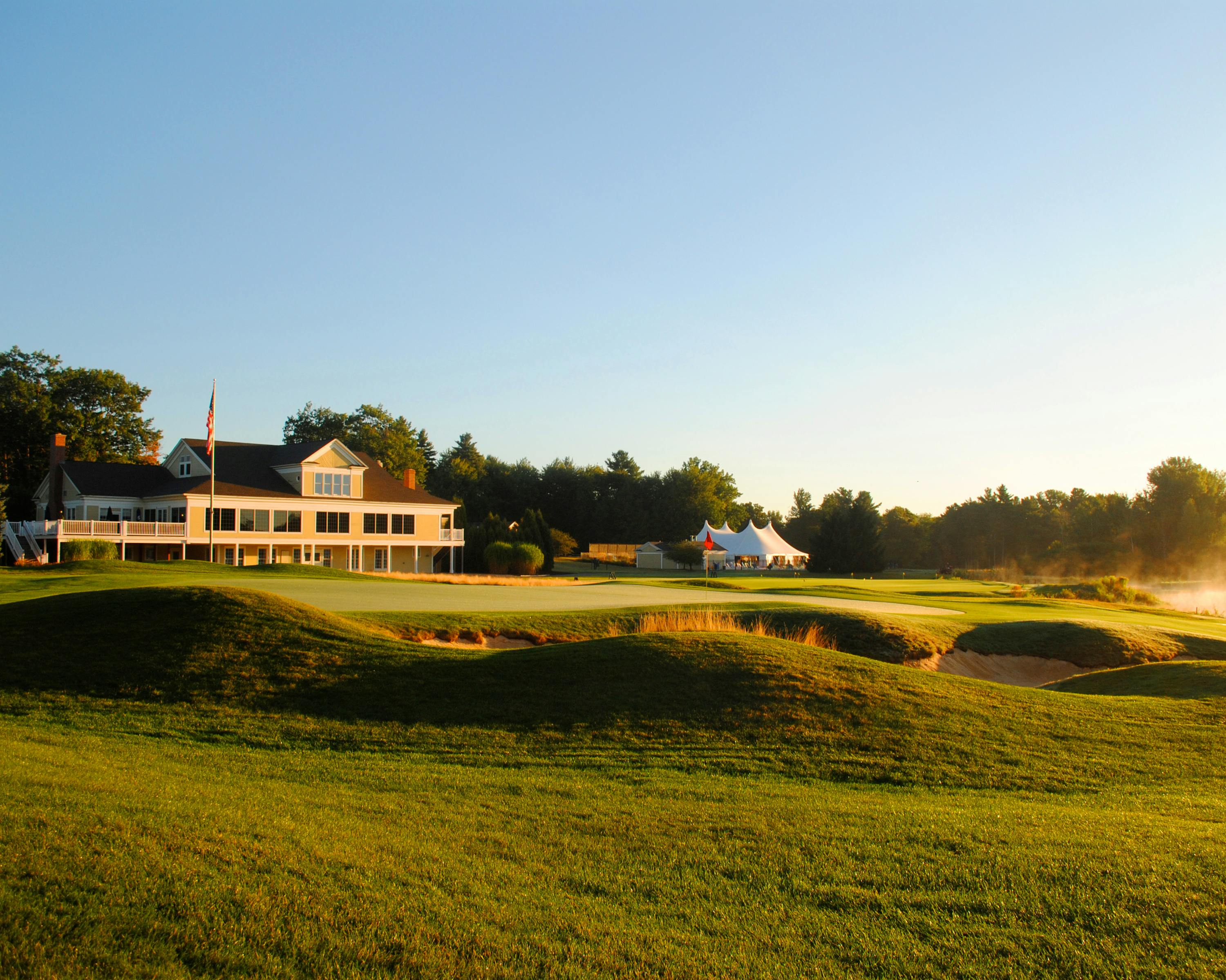 cottage on grassy hill near golf course under cloudless blue sky