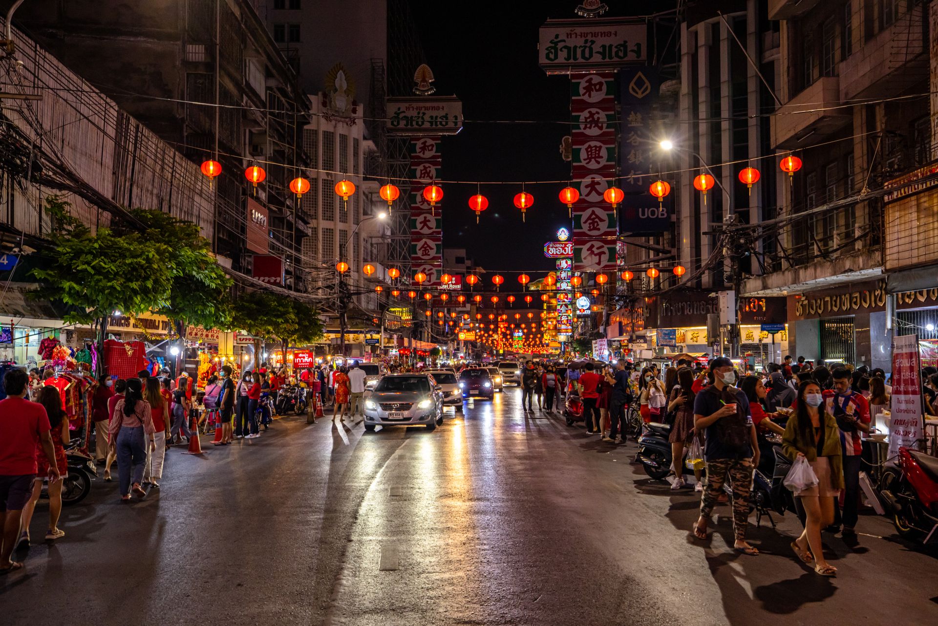 Street scene in Bangkok's Chinatown with red lanterns and bustling night market.