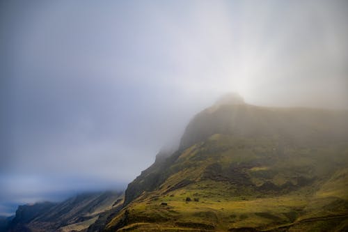 Sun behind mountain ridge with misty clouds on peaks