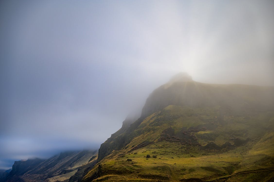 Sun behind mountain ridge with misty clouds on peaks