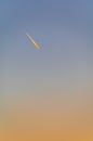Low angle of single sphere with falling comet in cloudless gradient bright sky in evening