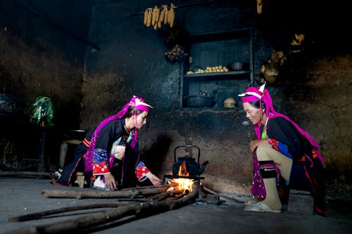 Women in Traditional Clothing Making Fire Indoors