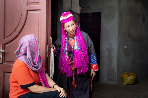 Free Two women in traditional Vietnamese clothing interact at an open door, showcasing cultural attire. Stock Photo