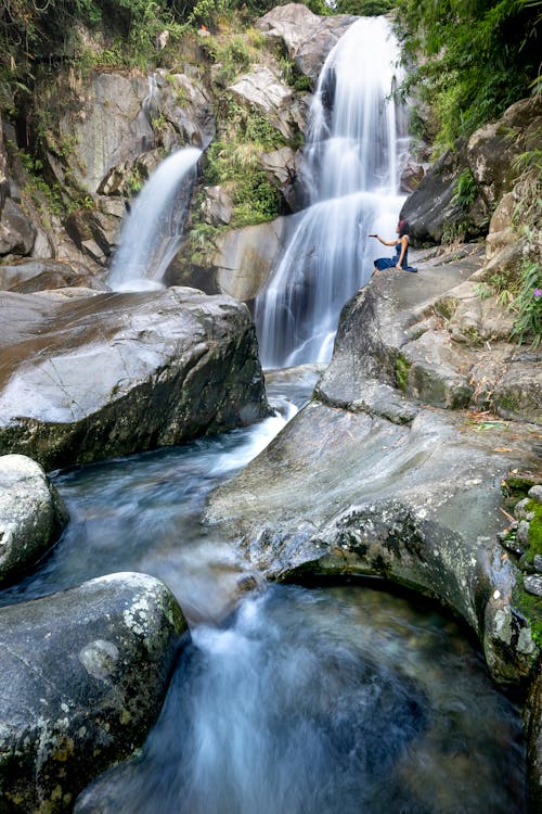 A Person Sitting near the Waterfall