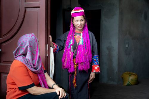 Free Woman in vibrant traditional Vietnamese clothing interacting in a home setting. Stock Photo