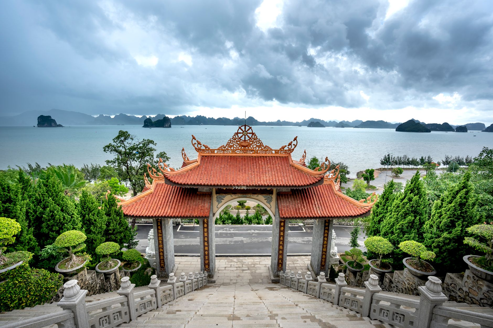Beautiful Asian pagoda overlooking tranquil lake and distant islands under dramatic clouds.