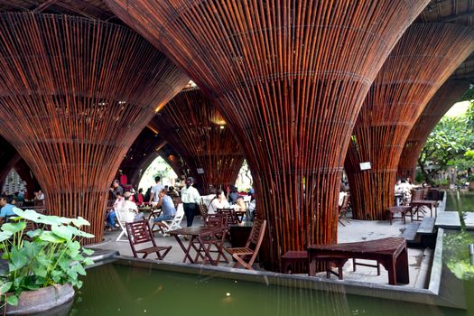 A bustling restaurant with unique bamboo architecture, vibrant ambiance, and lively atmosphere.