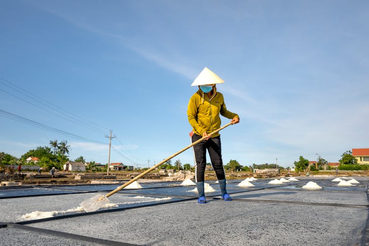 Man Spreading Salt With A Shovel As A Part Of Salt Evaporation Process