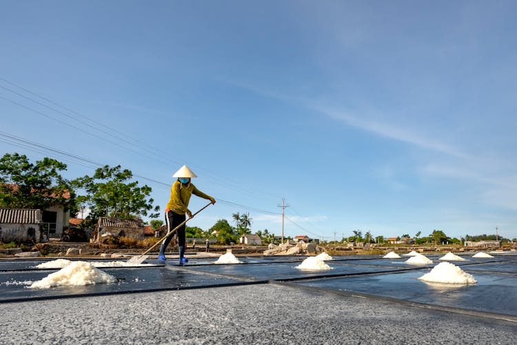 Man Spreading Salt With A Shovel As A Part Of Salt Evaporation Process