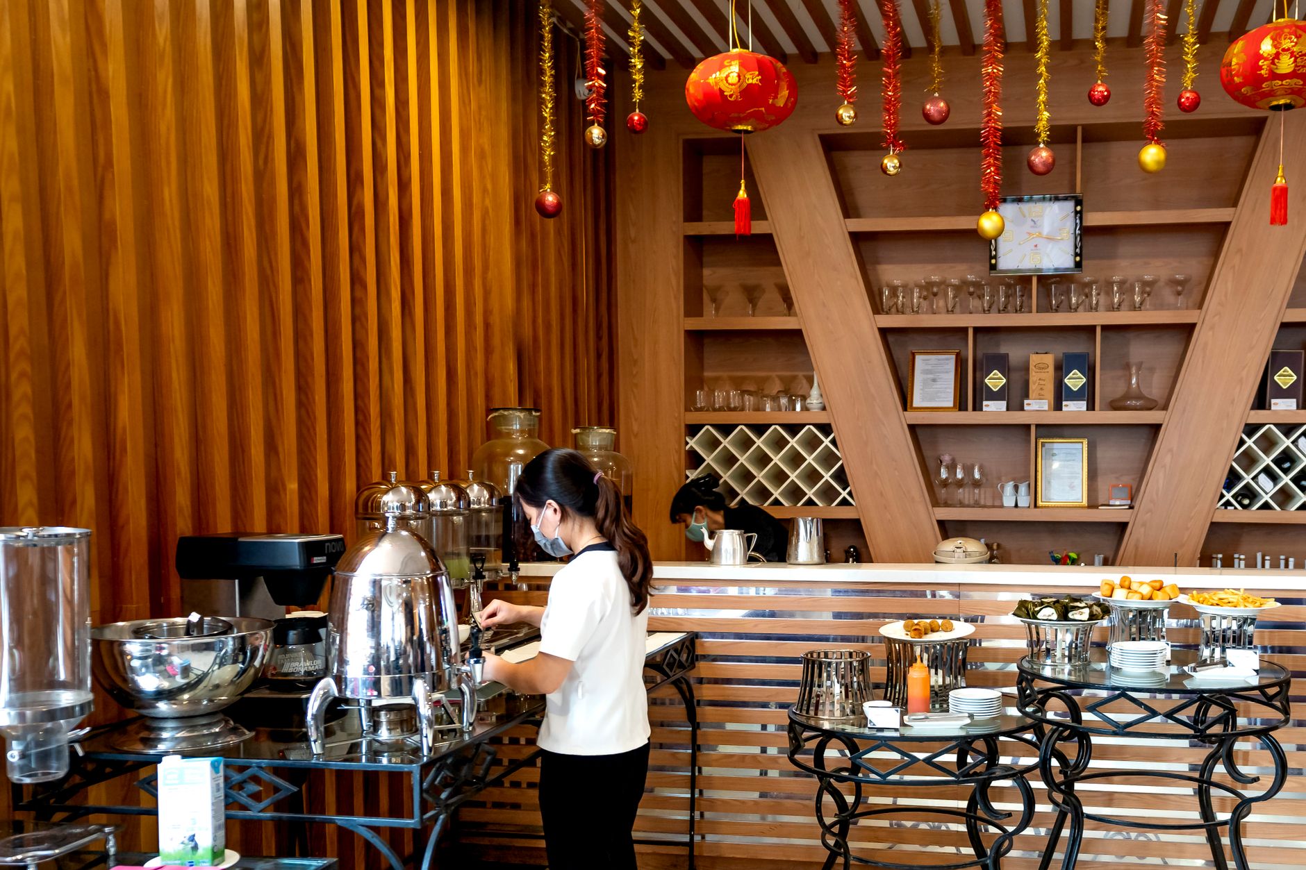 A modern buffet with festive decor and a person serving coffee, showcasing a sleek restaurant design.
