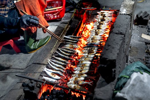 Close-up of fish grilling over a charcoal fire at an outdoor market, highlighting culinary tradition.