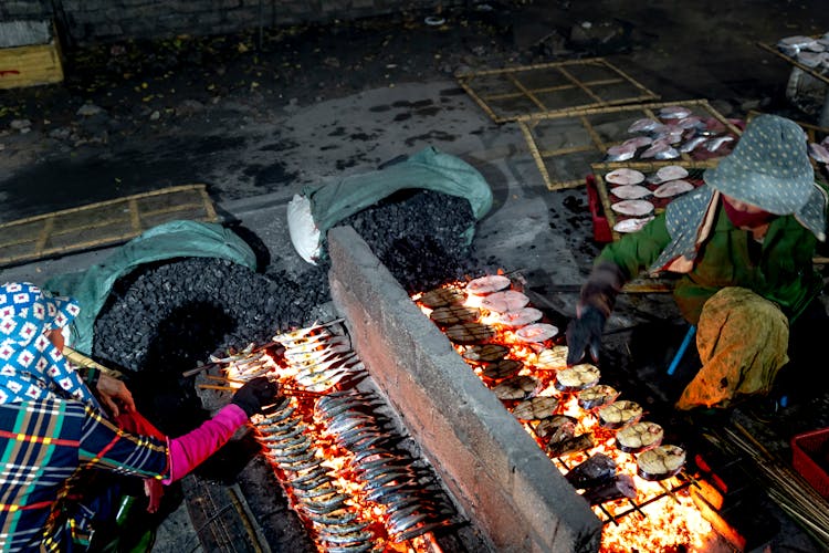 Women Grilling Fish In A Traditional Way On A Street Market 