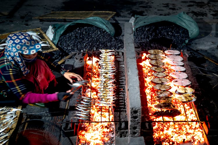 Woman Grilling Fish On A Market 