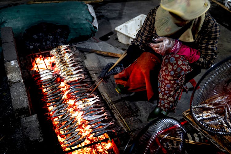 Person Cooking Fish On Traditional Grill