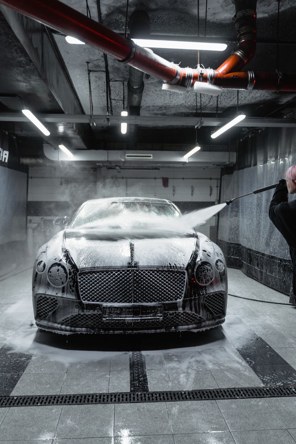 A luxury coupe covered in foam during a hand wash
