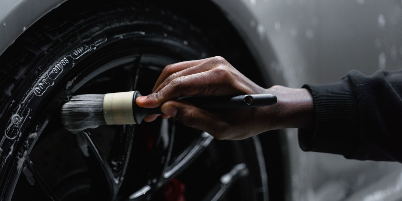 A detailer scrubbing a wheel and tire with a soft brush