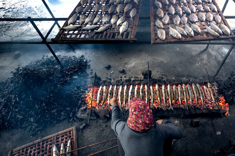 Man Frying Fish Over Burning Coal