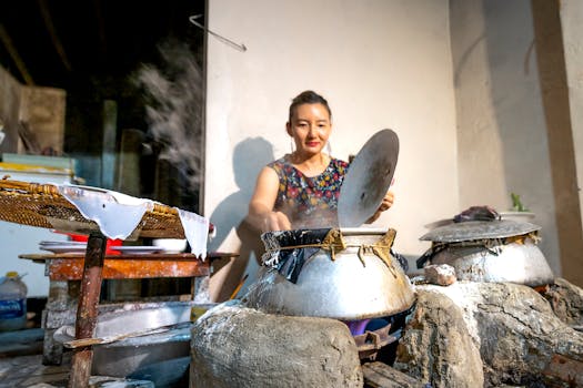Asian woman cooking in traditional outdoor kitchen with steaming pots. Rustic and cultural scene.
