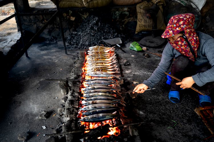 Woman Cooking Fish On Traditional Grill