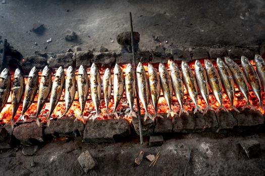 Array of fish grilling on an open fire pit for traditional cooking.