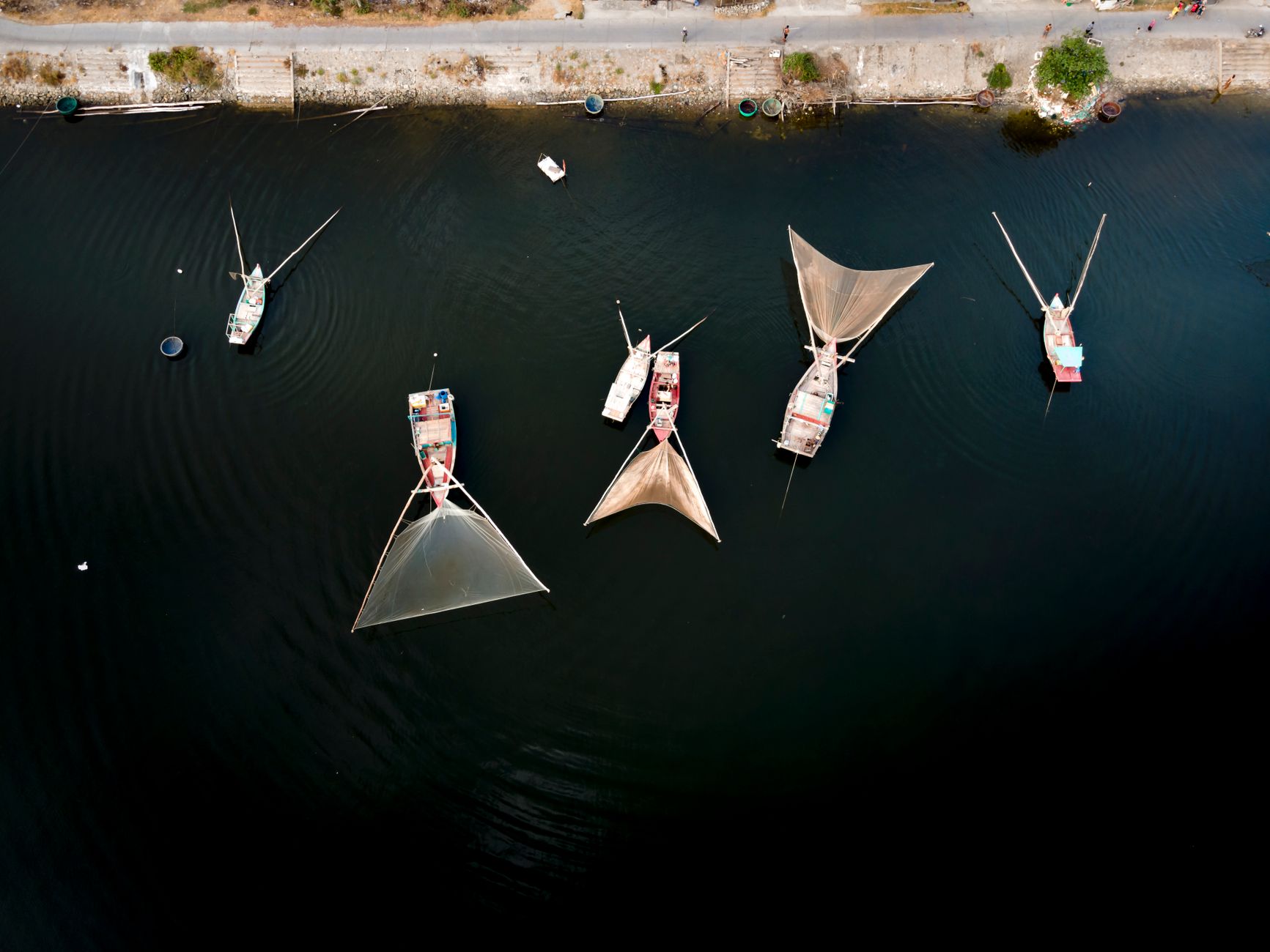 Top view of boats with large nets in open water, showcasing traditional fishing methods from above.