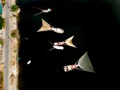 Overhead shot of traditional sailing boats with distinct triangular sails on calm, dark water.