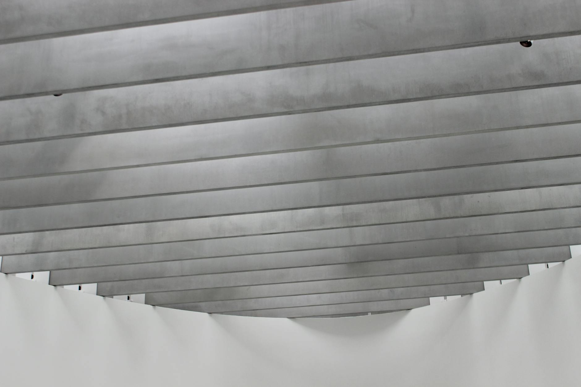 A minimalist grey architectural ceiling with metal beams.