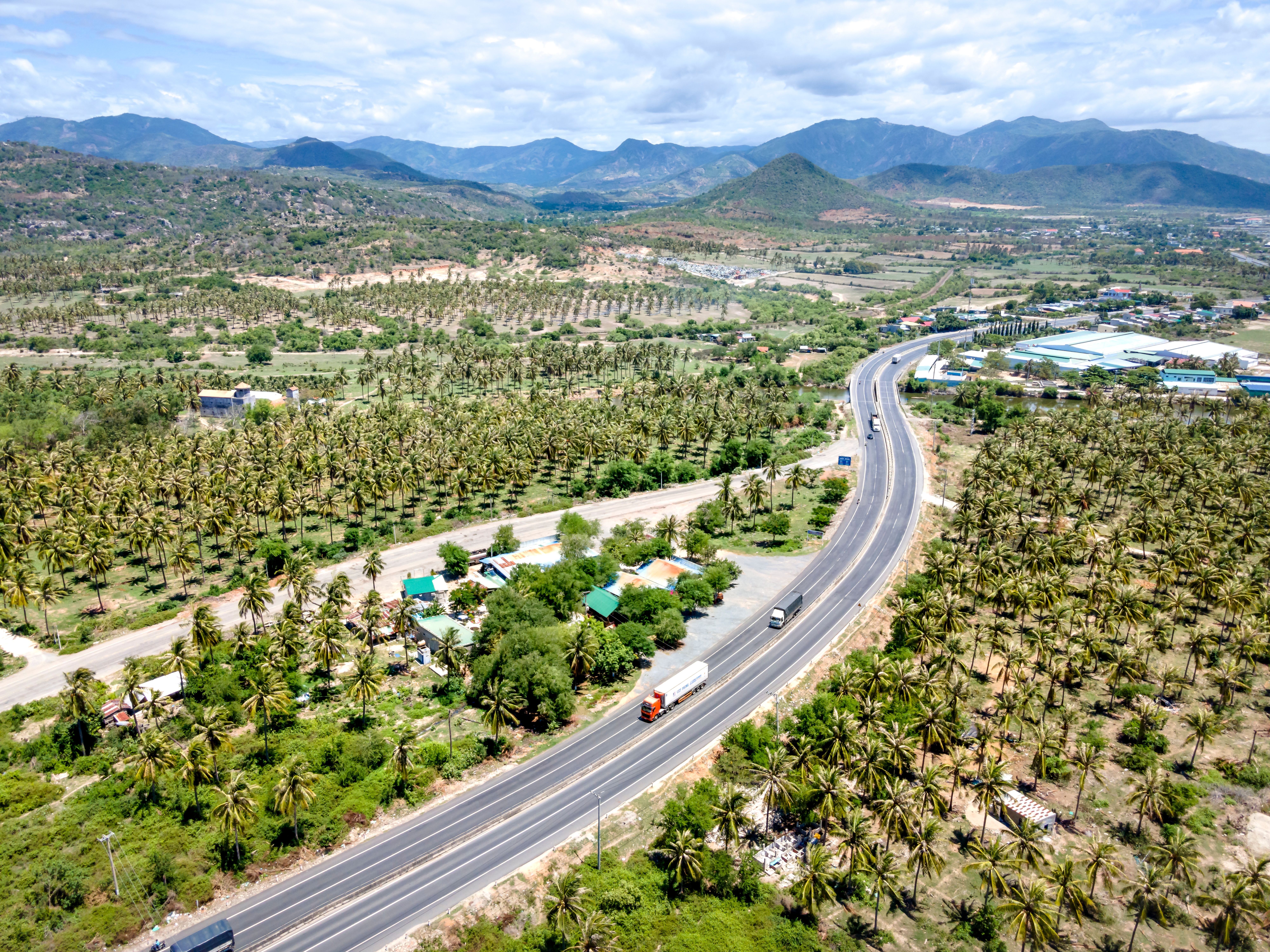 Stunning aerial view of a highway winding through a tropical landscape with distant hills.