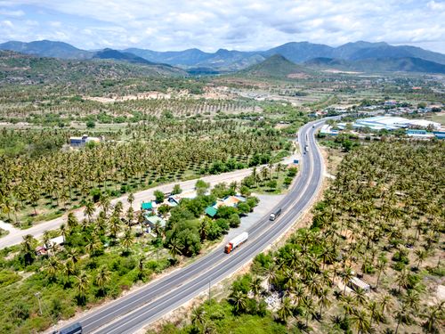 Free Stunning aerial view of a highway winding through a tropical landscape with distant hills. Stock Photo