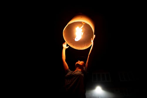 Free A Person Holding a Sky Lantern with Flame Stock Photo