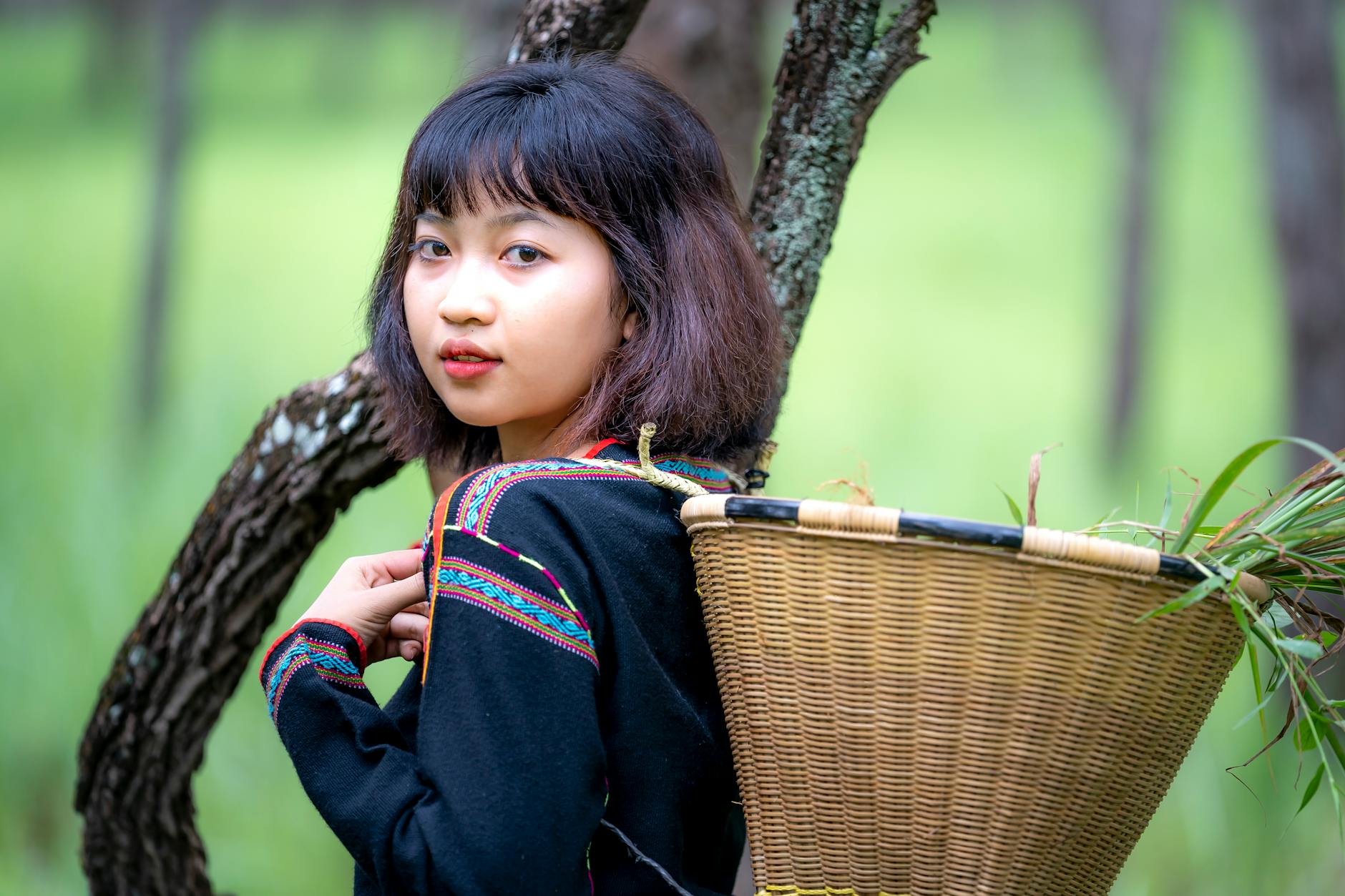 Portrait of a young woman carrying a basket in a lush forest.