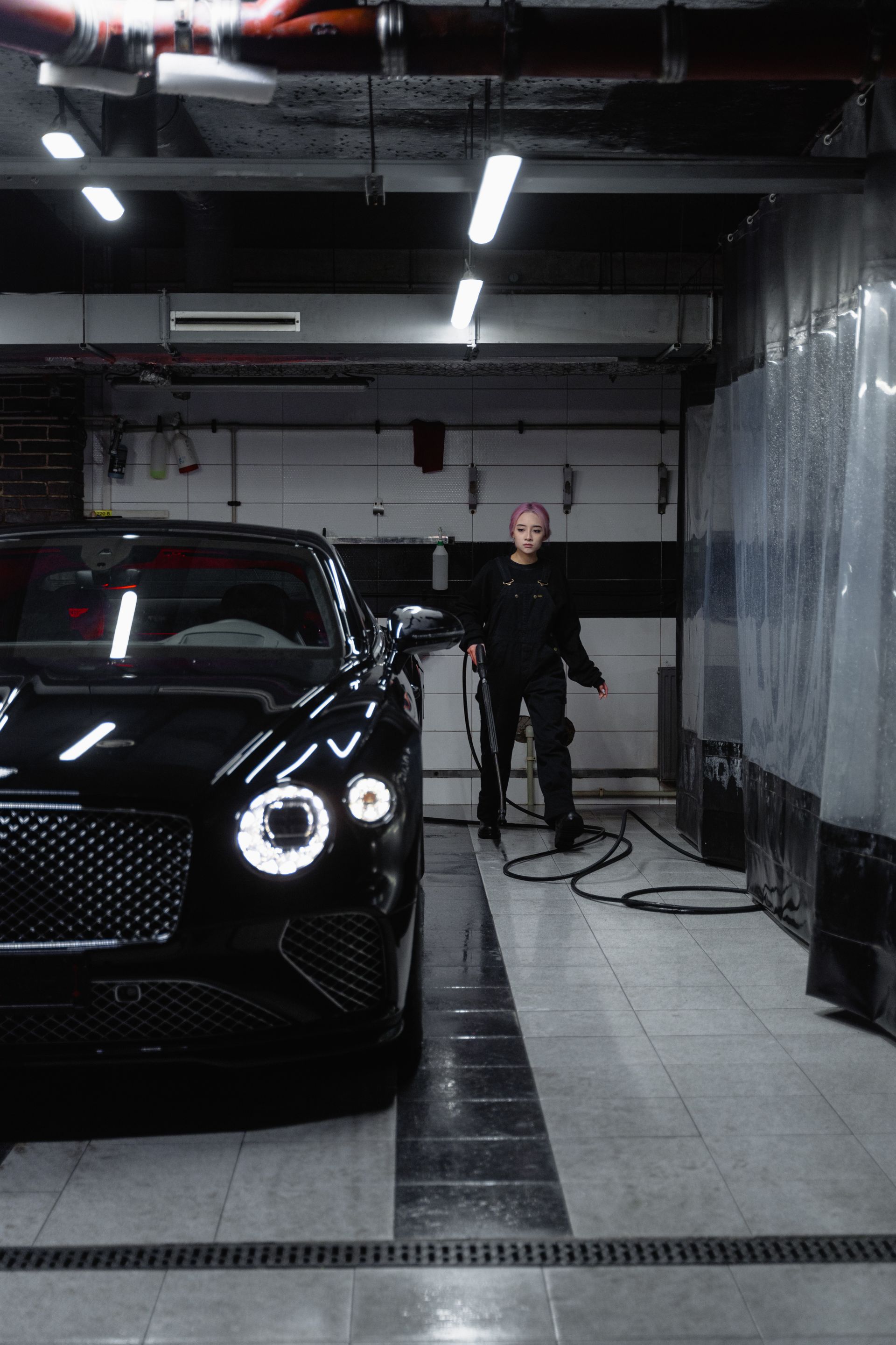 Black car gleaming inside a modern detailing studio
