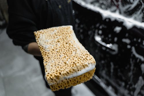 A person using a sponge in washing car