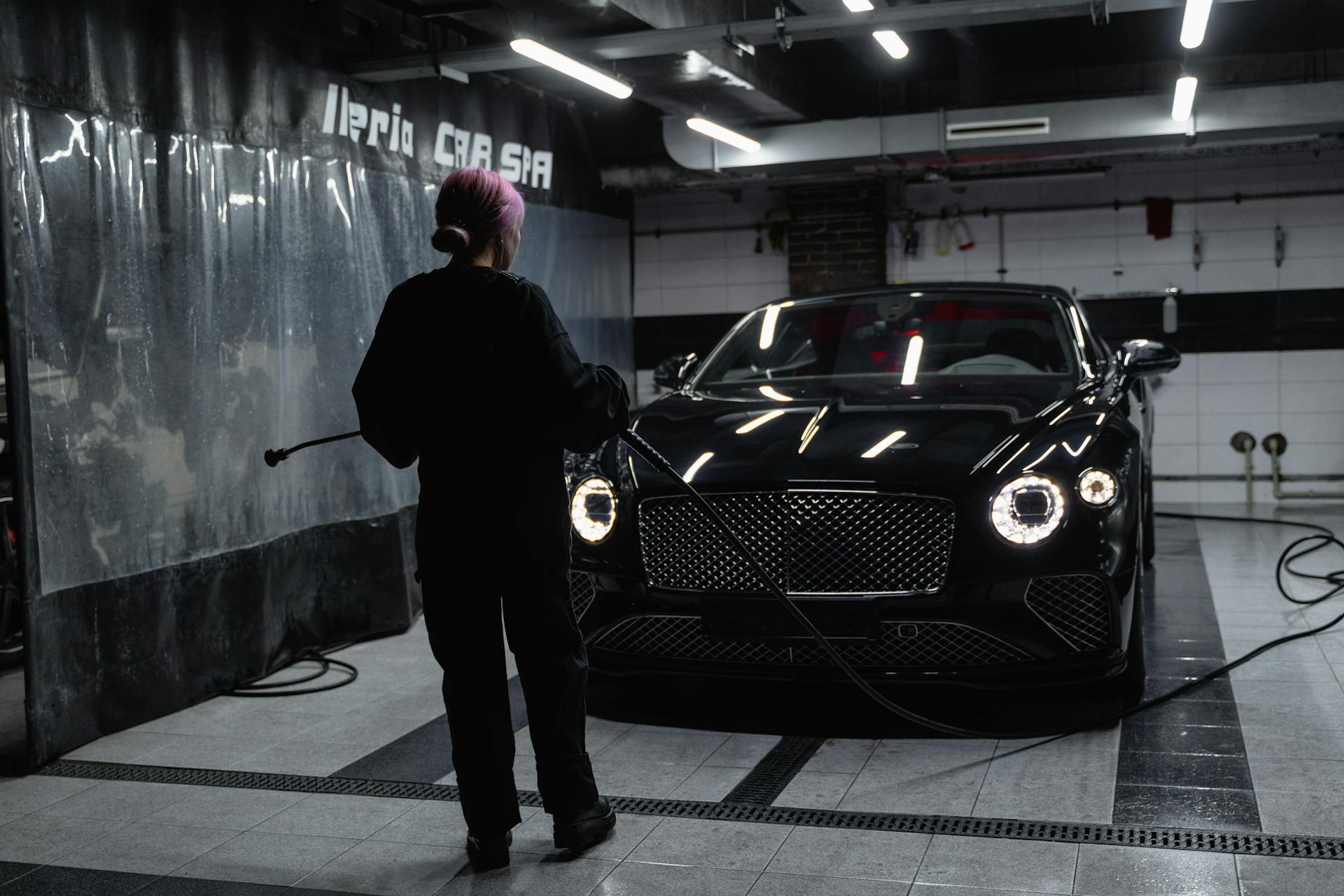 A luxury car being washed inside a car service garage by a professional.