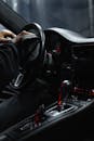 Person in Black Long Sleeves Sitting on the Driver's Seat while Wiping the Stirring Wheel