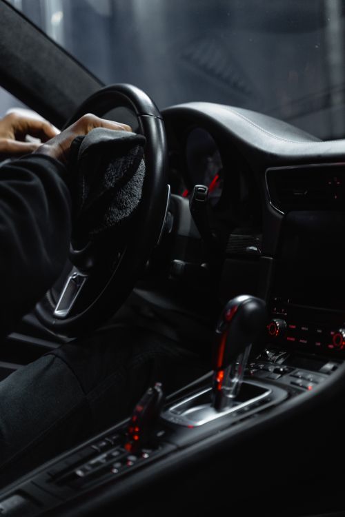 Person carefully cleaning a premium vehicle steering wheel and dashboard